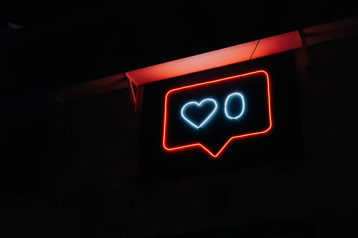 A neon sign showing zero likes on a social media post