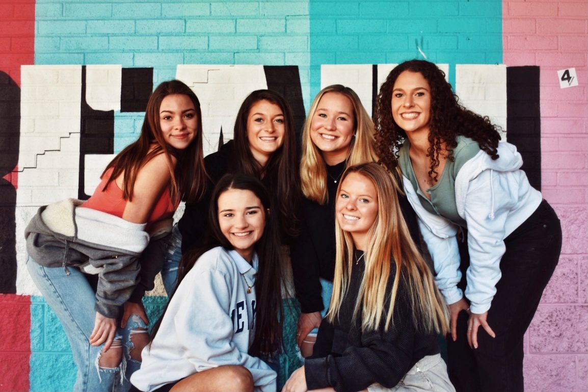 A group of teenage girls pose and smile happily