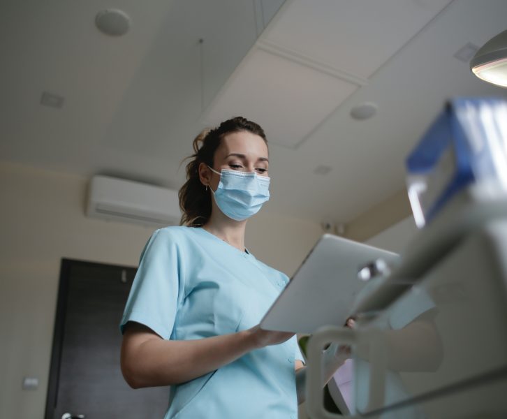 An image of a nurse with a medical mask on in a medical building setting. Symbolizes how to navigate health insurance as a young adult.