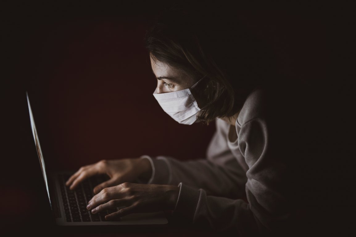 Person wearing mask and looking at a computer screen.
