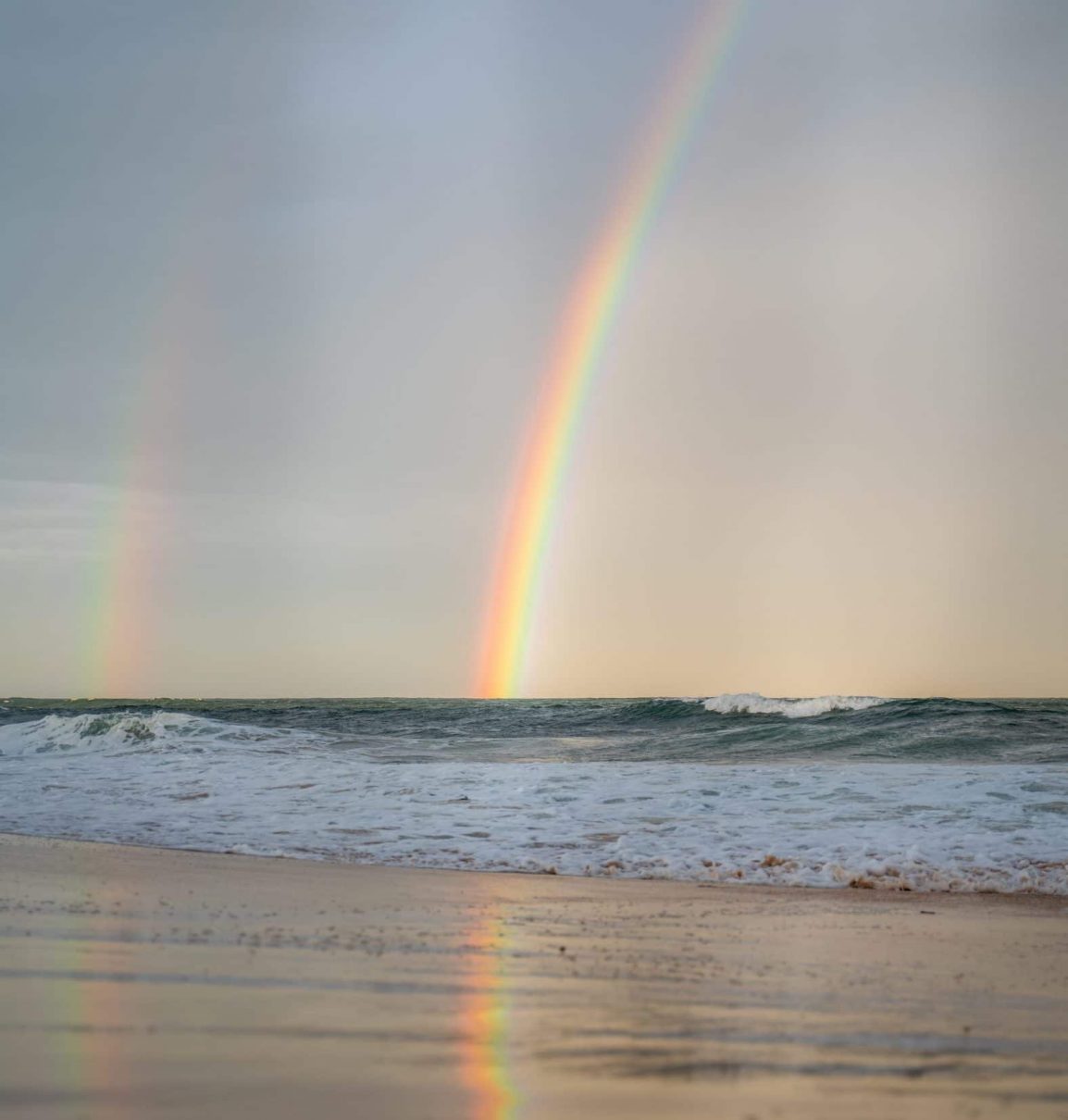 rainbow and its reflection on the beach
