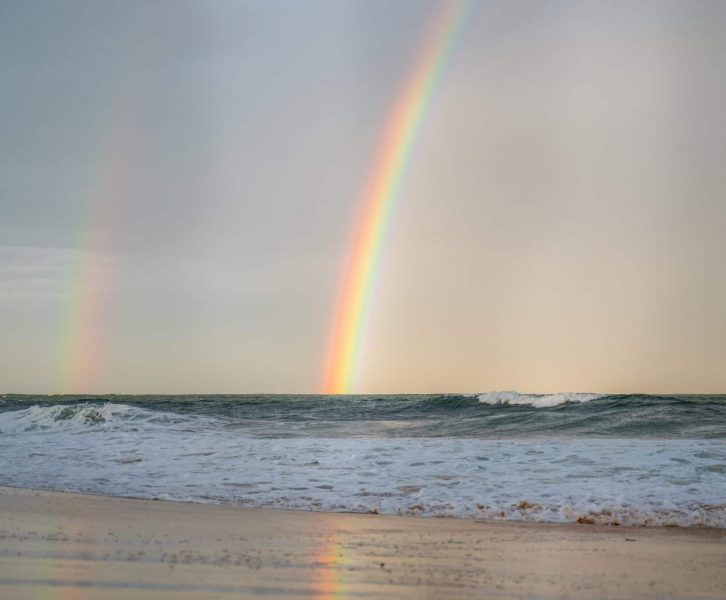 rainbow and its reflection on the beach